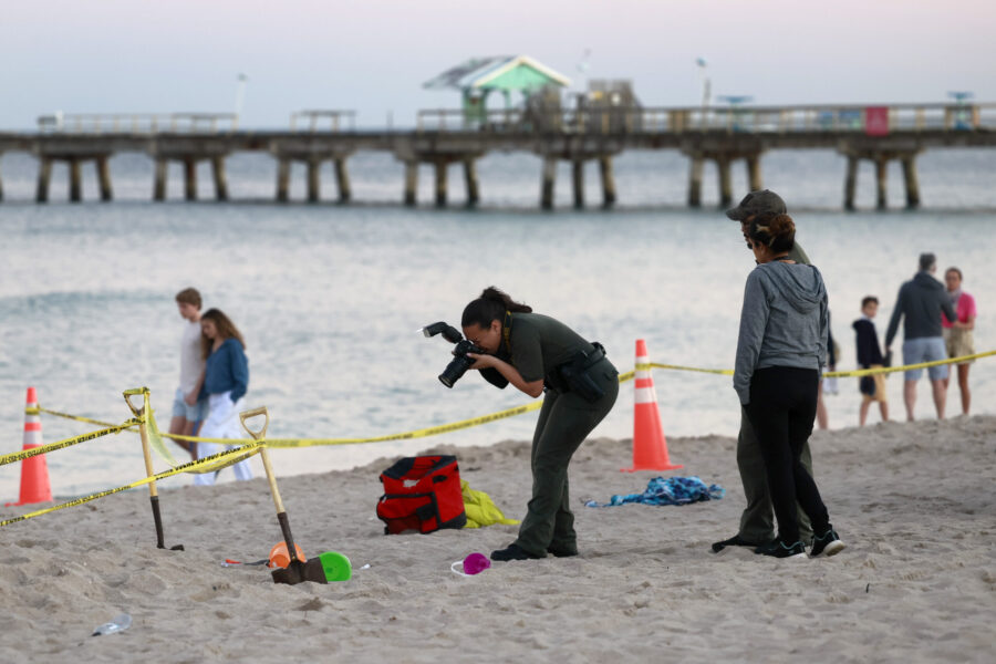 Investigators on the beach in Lauderdale-by-the-Sea, Fla., take photos of the scene of a sand colla...