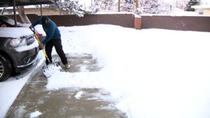 A man shovels snow with a traditional snow shovel