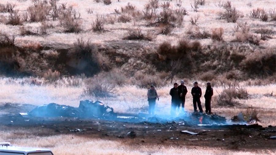 emergency crews stand around the scorched remains of an airplane...