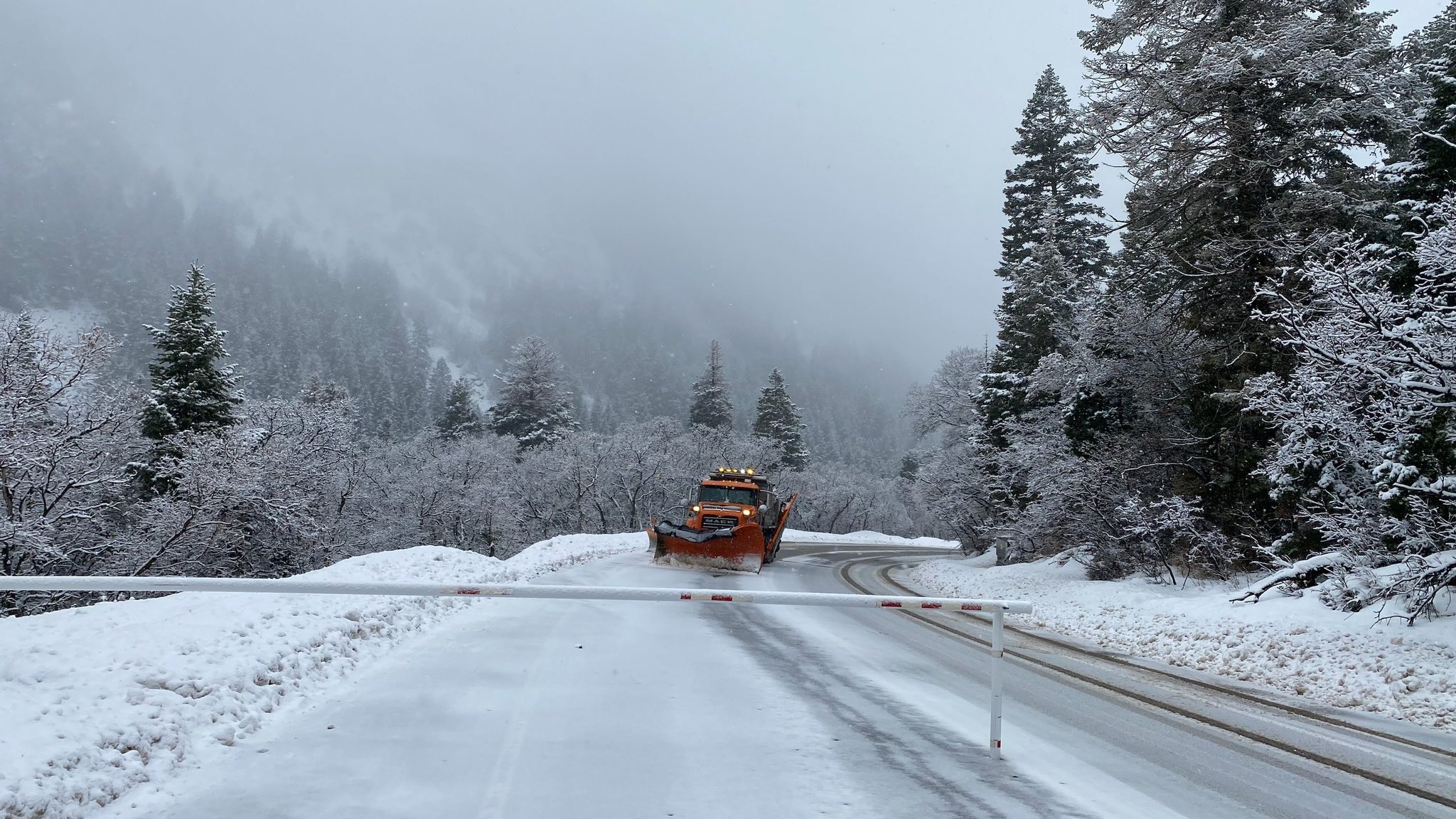 A UDOT snowplow works in Little Cottonwood Canyon near a road closure gate. (@UDOTcottonwoods, X)...