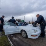 Officers with the Salt Lake City Police Department search a white passenger car after arresting the driver as part of a drug investigation. (Salt Lake City Police Department)