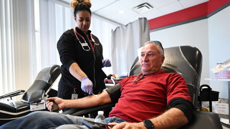 Dennis Druce is assisted in his blood donation by technician Shea Proctor at the American Red Cross...