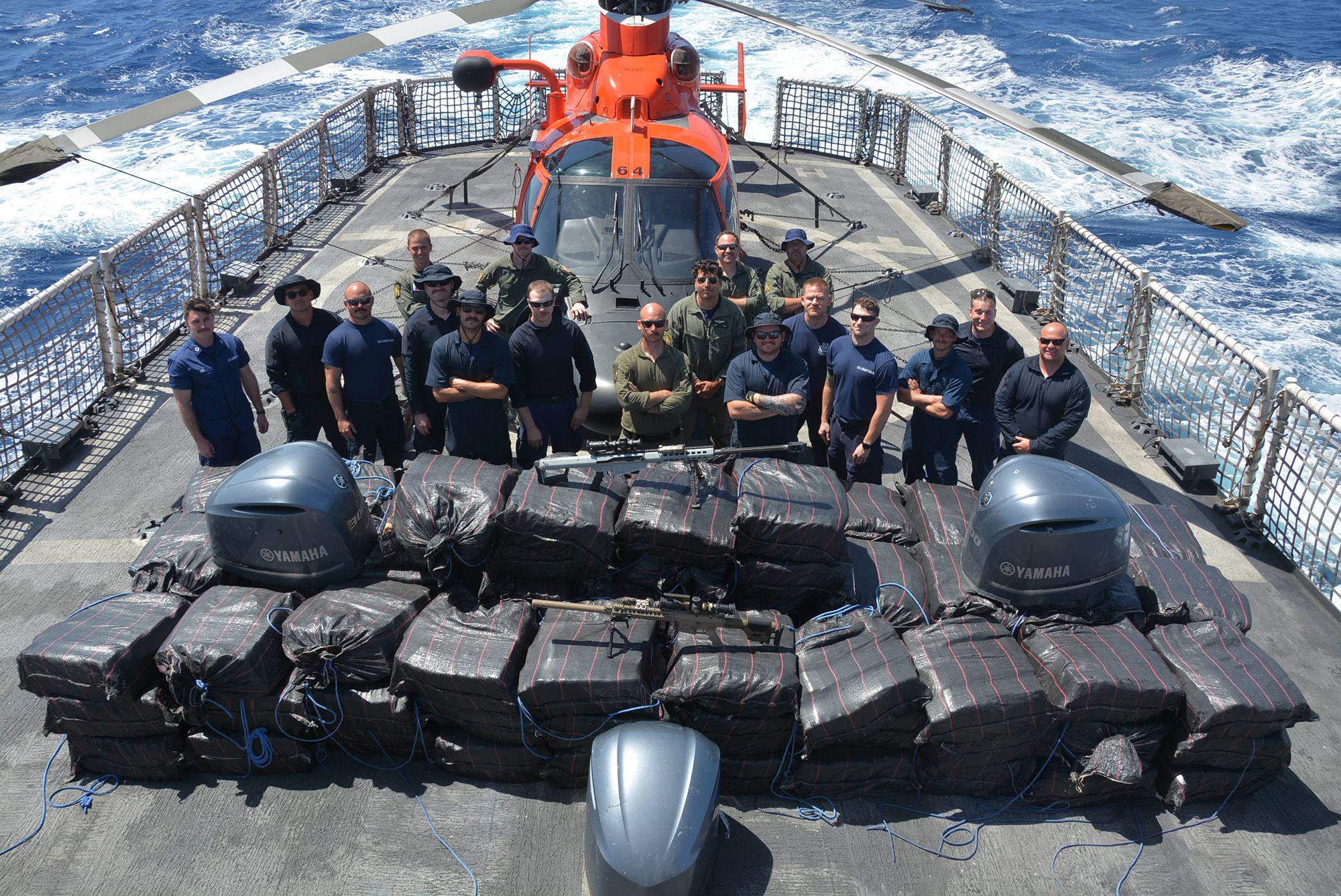 Crewmembers of the Coast Guard Cutter Alert (WMEC 630) stand behind cocaine bales seized from a dru...
