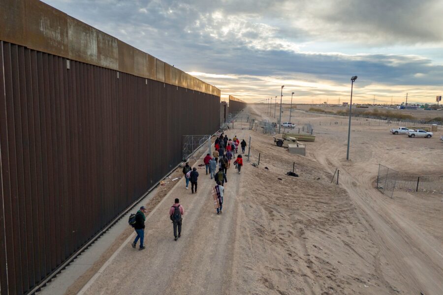 Migrants walk along the US-Mexico border wall after crossing the Rio Grande into El Paso, Texas, fr...