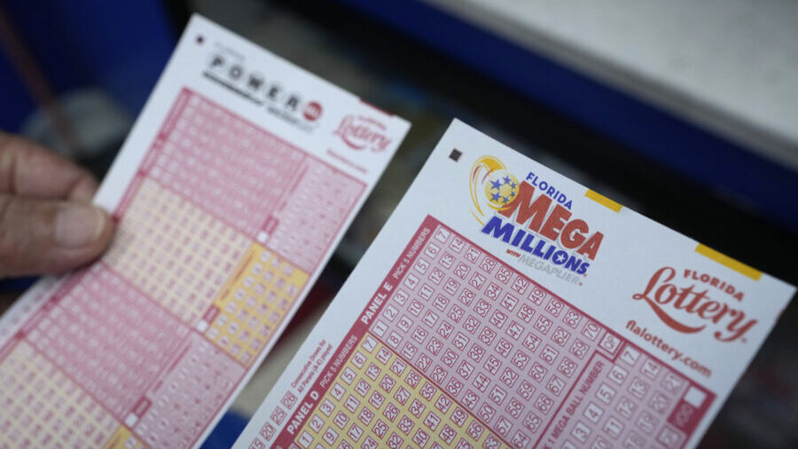 FILE - A lottery player holds forms to pick numbers for the Powerball and Mega Millions lotteries a...