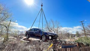A Hyundai Sonata is lifted out of the backyard of a resident's home rests in tree after it sailed over an alley, Washington City, Utah, March 6, 2024.