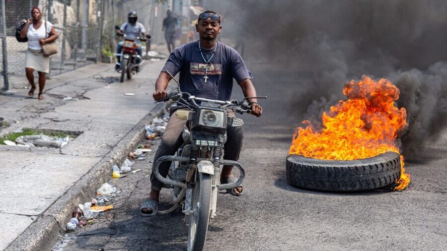 A motorcyclist passes burning tires during a demonstration against CARICOM, in Port-au-Prince, Hait...