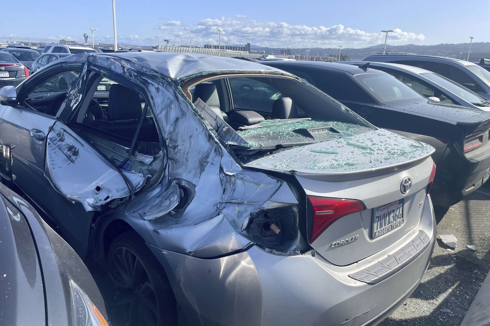 A damaged car is seen in an employee parking lot after tire debris from a United Airlines plane lan...