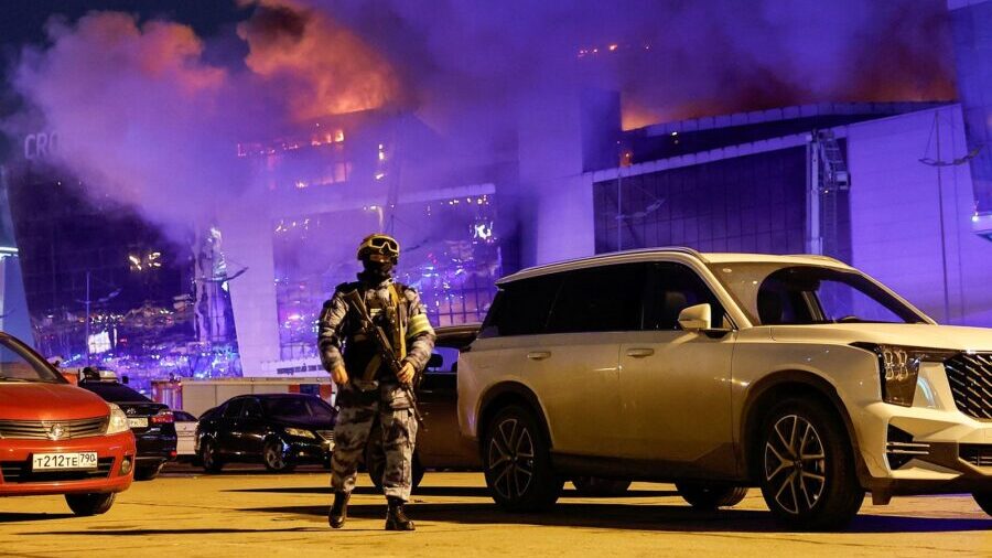 A Russian law enforcement officer near the burning Crocus City Hall concert venue following a shoot...