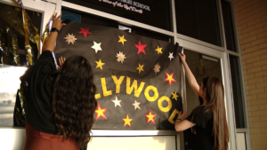 Two friends hang a paper "Hollywood" sign