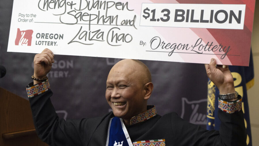 Cheng "Charlie" Saephan holds a check above his head after speaking during a news conference where ...