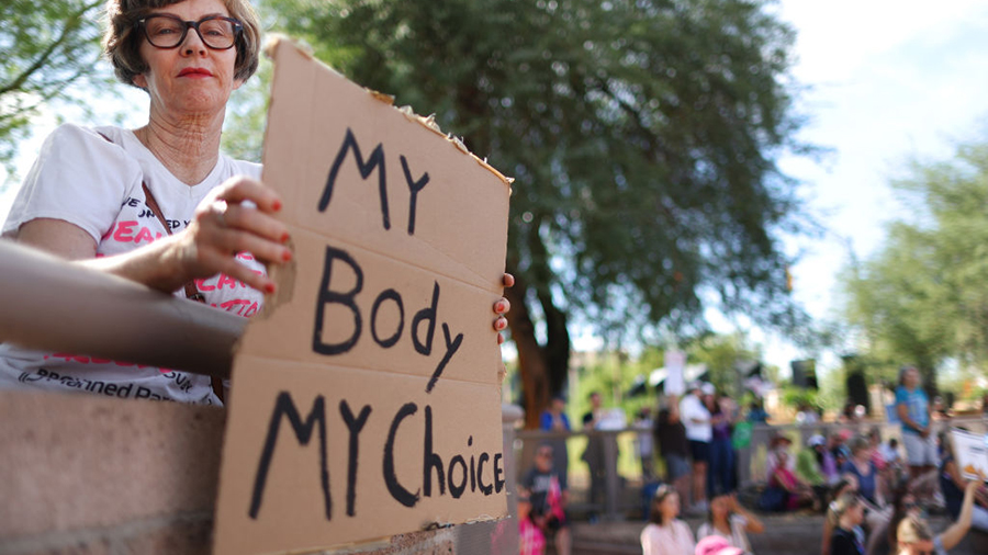A protestor holds a sign reading 'My Body My Choice' at a Women's March rally where Arizona Secreta...