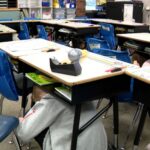 Student waits under their desk during the earthquake simulation