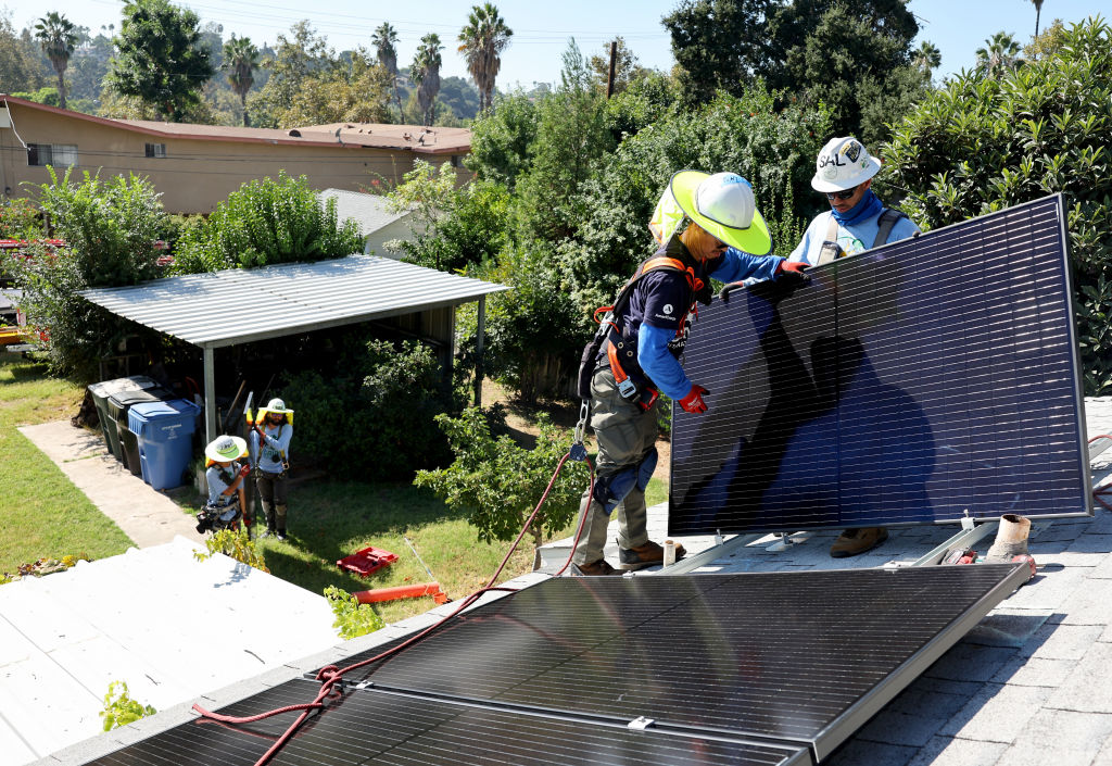 FILE: GRID Alternatives employees Tony Chang (L) and Sal Miranda install no-cost solar panels on th...