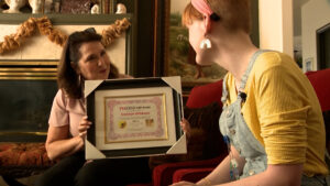 Rebecca Cressman handing Gracelyn Wilkinson her certificate of recognition.
