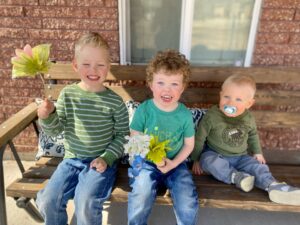 (From left to right) 7-year-old Liam, 5-year-old Ollie, and 3-year-old Milo, sitting on a bench together. 
