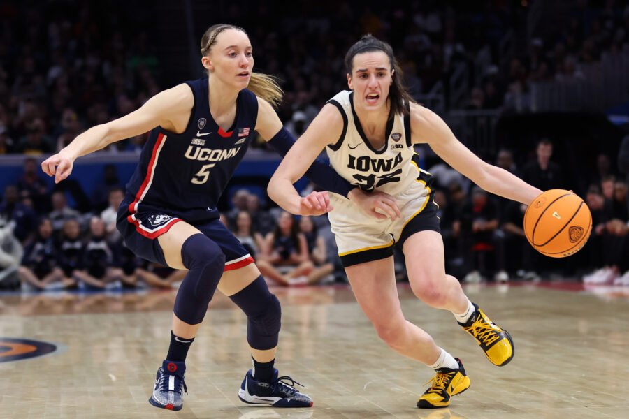 Caitlin Clark #22 of the Iowa Hawkeyes dribbles around Paige Bueckers #5 of the UConn Huskies in th...