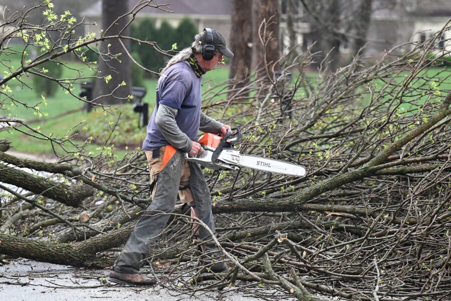 A worker cut up downed tress lying across the road following severe storms that passed through Pros...
