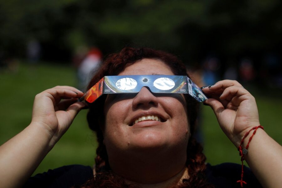 A woman uses eclipse glasses to observe an annular solar eclipse at the Bicentenario Park in Antigu...