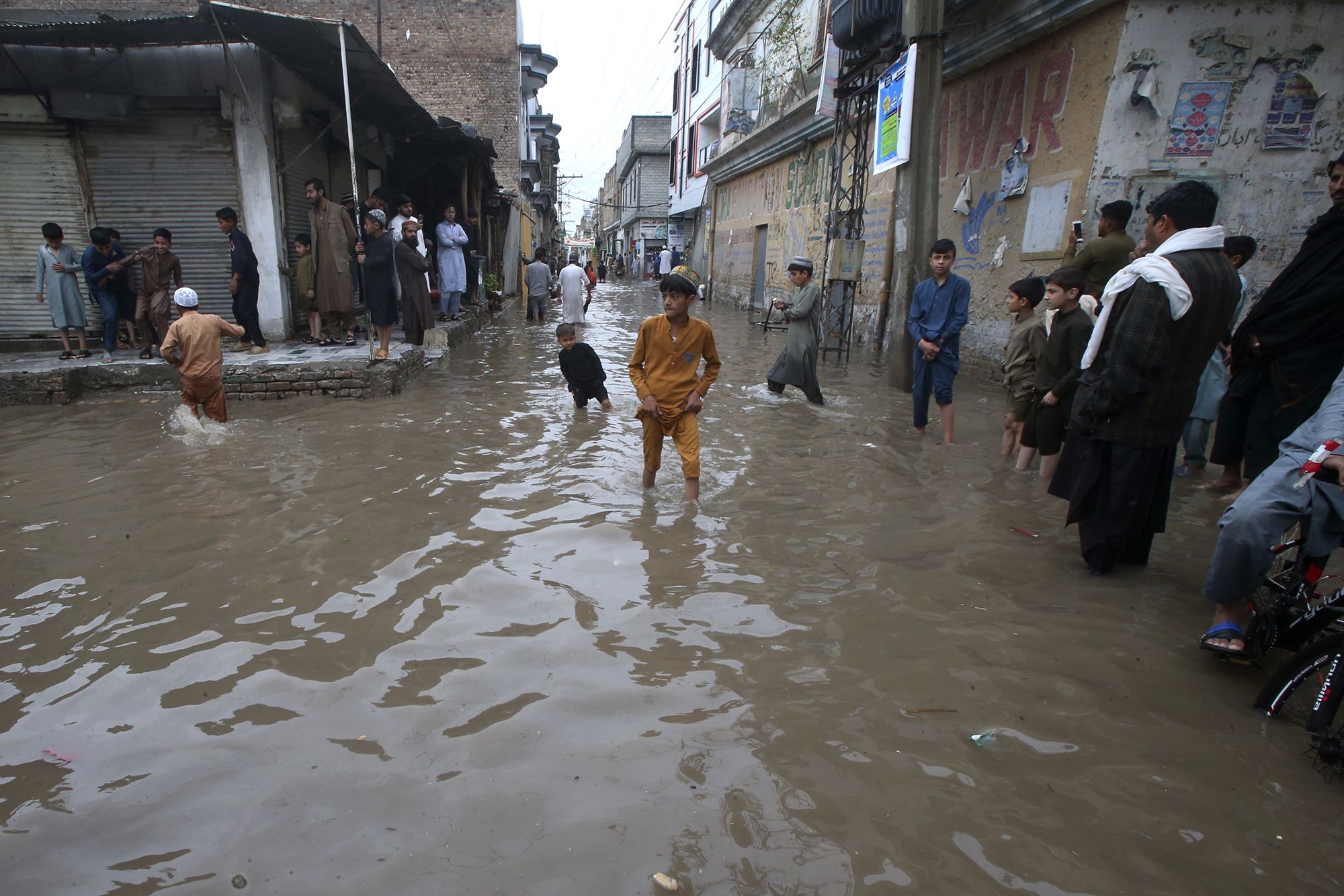 People wade through a street flooded by heavy rain in Peshawar, Pakistan on Monday, April 15.
Manda...
