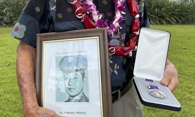 Wilfred Ikemoto holds a photo of his older brother, Haruyuki Ikemoto, and the Purple Heart medal po...