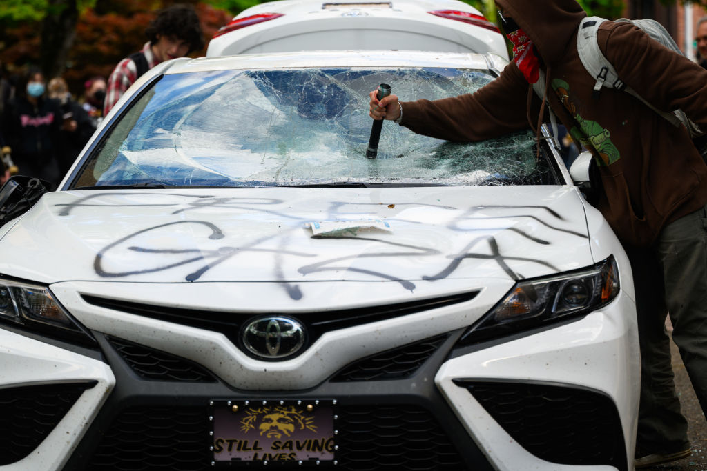PORTLAND, OREGON - MAY 2: Protesters deface a car after a counter-protester drove towards the crowd...
