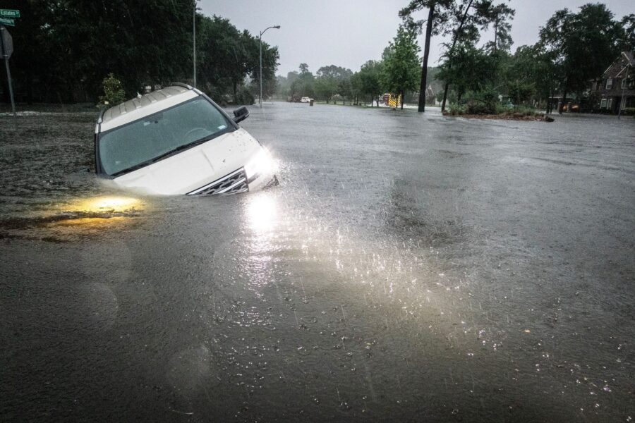 An SUV is stranded in a ditch along a stretch of street flooding during a severe storm Thursday in ...