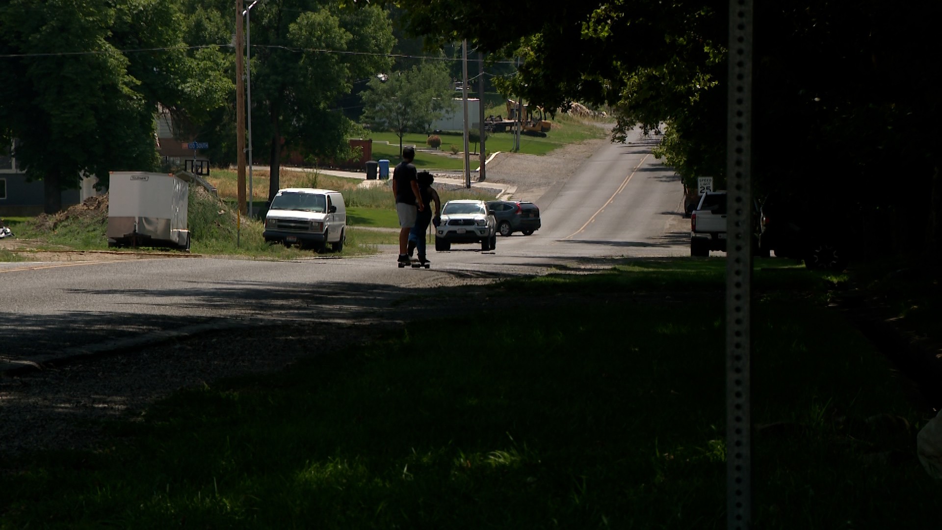 Two people on a scooter and skateboard riding down a street some residents say is unsafe for studen...