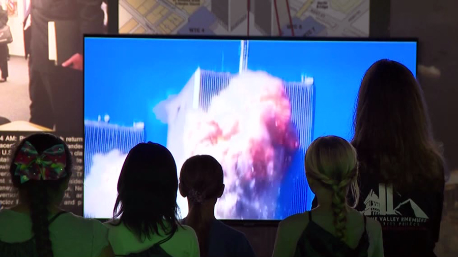 people watch screen of twin towers on 9/11...