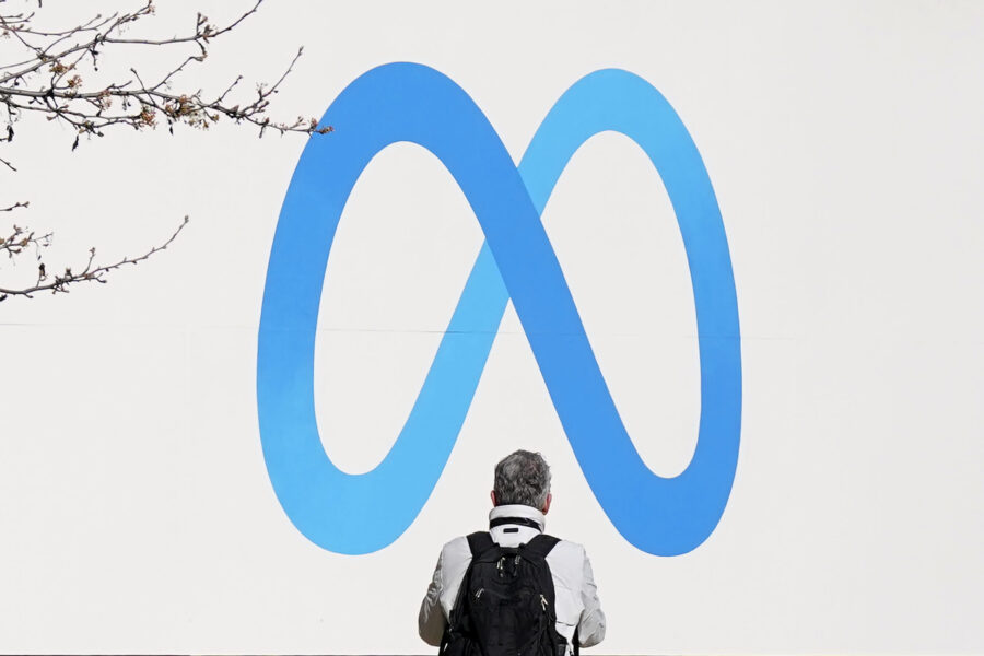 FILE - A person stands in front of a Meta sign outside of the company's headquarters in Menlo Park,...