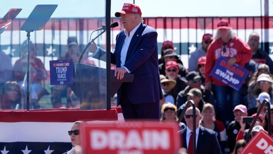 Former President Donald Trump, pictured speaking behind bullet-resistant glass during a campaign ev...