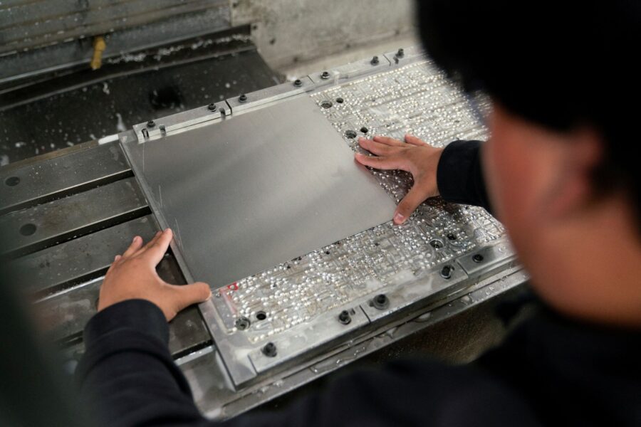 A worker places metal in a milling machine while producing parts for a Boeing 777 jetliner at Pathf...