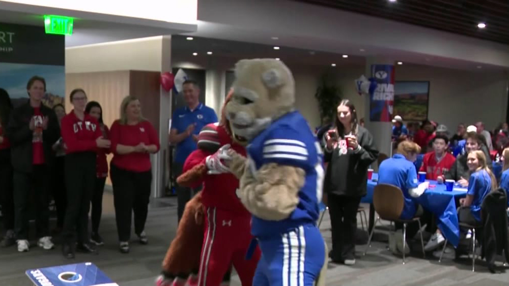 Two mascots engage in front of crowds...